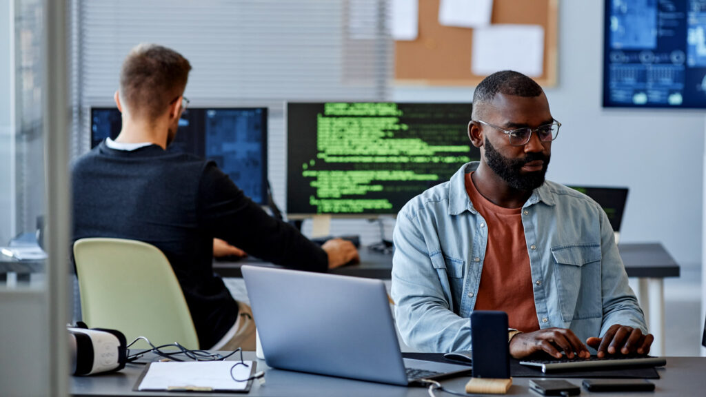 Services IBM i Development Featured Image showing two computer programmers working in an office