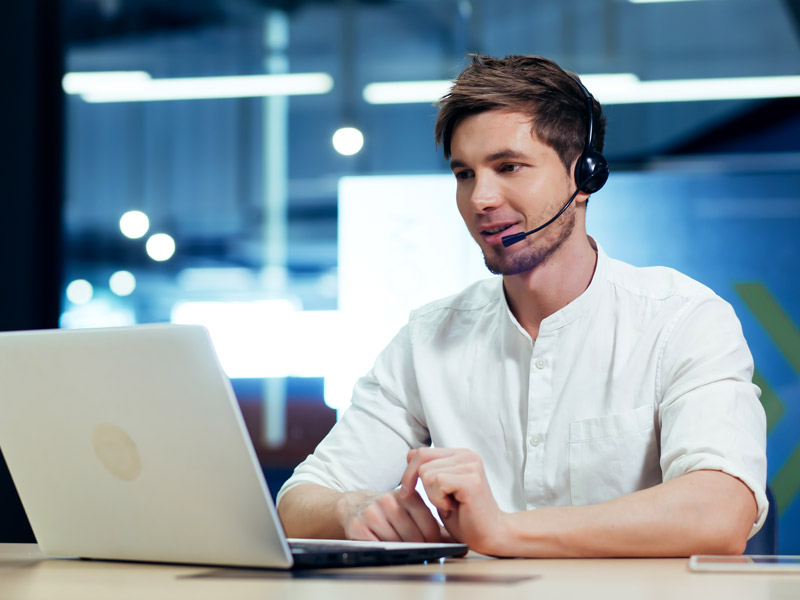 Support worker provides SLA backed support services for a customer using a video call on a laptop with headset