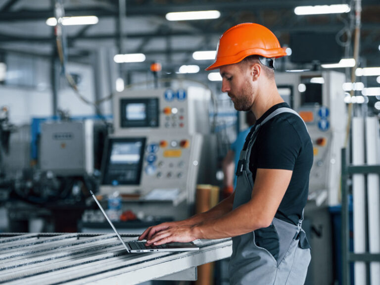 Factory worker uses laptop to access information from connected systems on factory floor