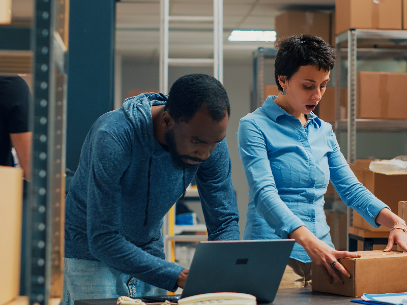 Retail workers in a warehouse working on a laptop