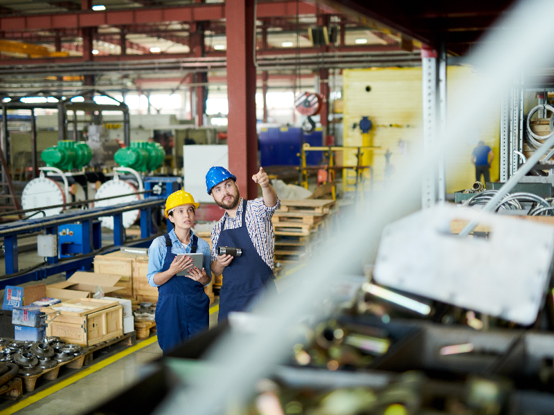 Two workers looking at manufacturing machinery