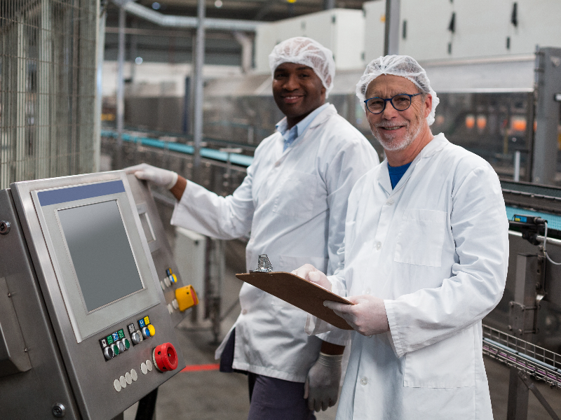 Two factory workers by a processing machine